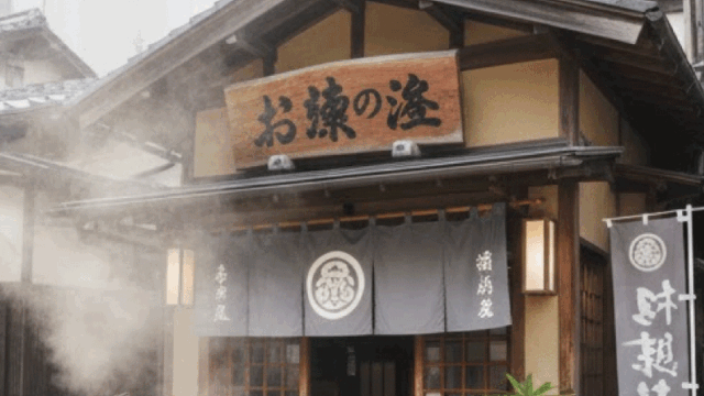 A bright and welcoming Japanese onsen entrance, daytime, traditional wooden building, soft steam rising, travel-friendly atmosphere, no people visible, clean and calm, realistic photography, warm natural light, inviting mood
