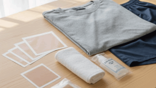 A travel flat-lay showing tattoo cover stickers, towels, and simple clothing on a wooden surface, realistic photography, bright natural light, clean and practical travel style